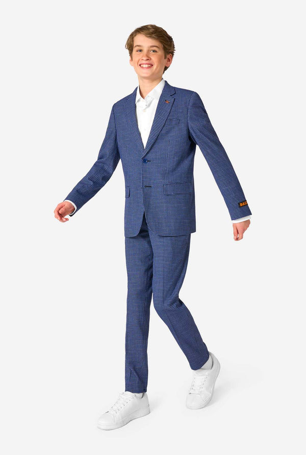 Een tienerjongen, gekleed in een marineblauw en blauw geruit pak met een wit overhemd. Het pak heeft een moderne pasvorm met twee knopen en klepzakken. Hij staat tegen een effen witte achtergrond. Volledig lichaam 