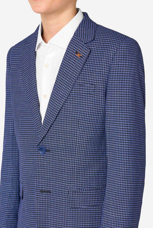 Een tienerjongen, gekleed in een marineblauw en blauw geruit pak met een wit overhemd. Het pak heeft een moderne pasvorm met twee knopen en klepzakken. Hij staat tegen een effen witte achtergrond. Close up van de borst