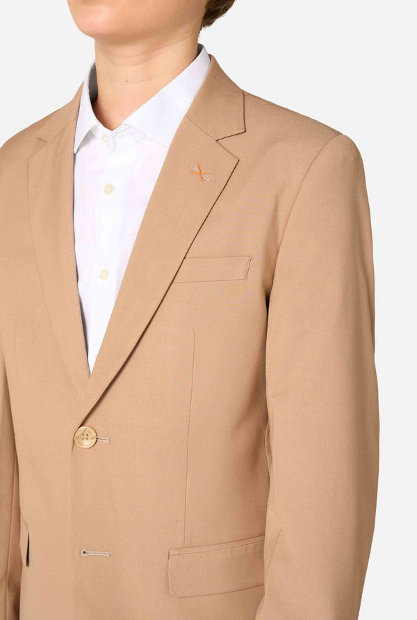 Tienerjongen draagt ​​een stijlvol lichtbruin/beige pak met een wit overhemd. Perfecte formele outfit voor speciale gelegenheden, bruiloften en feesten voor jongens. Close up van de borst.
