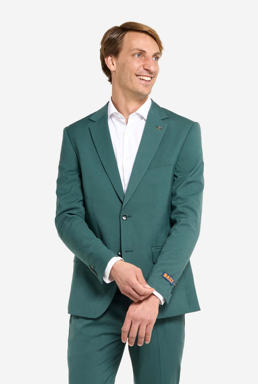 Afbeelding met lichtgrijze achtergrond en een man in een donkergroen herenpak en wit overhemd. Het pak bestaat uit een blazer en een pantalon. De man kijkt zijwaarts.