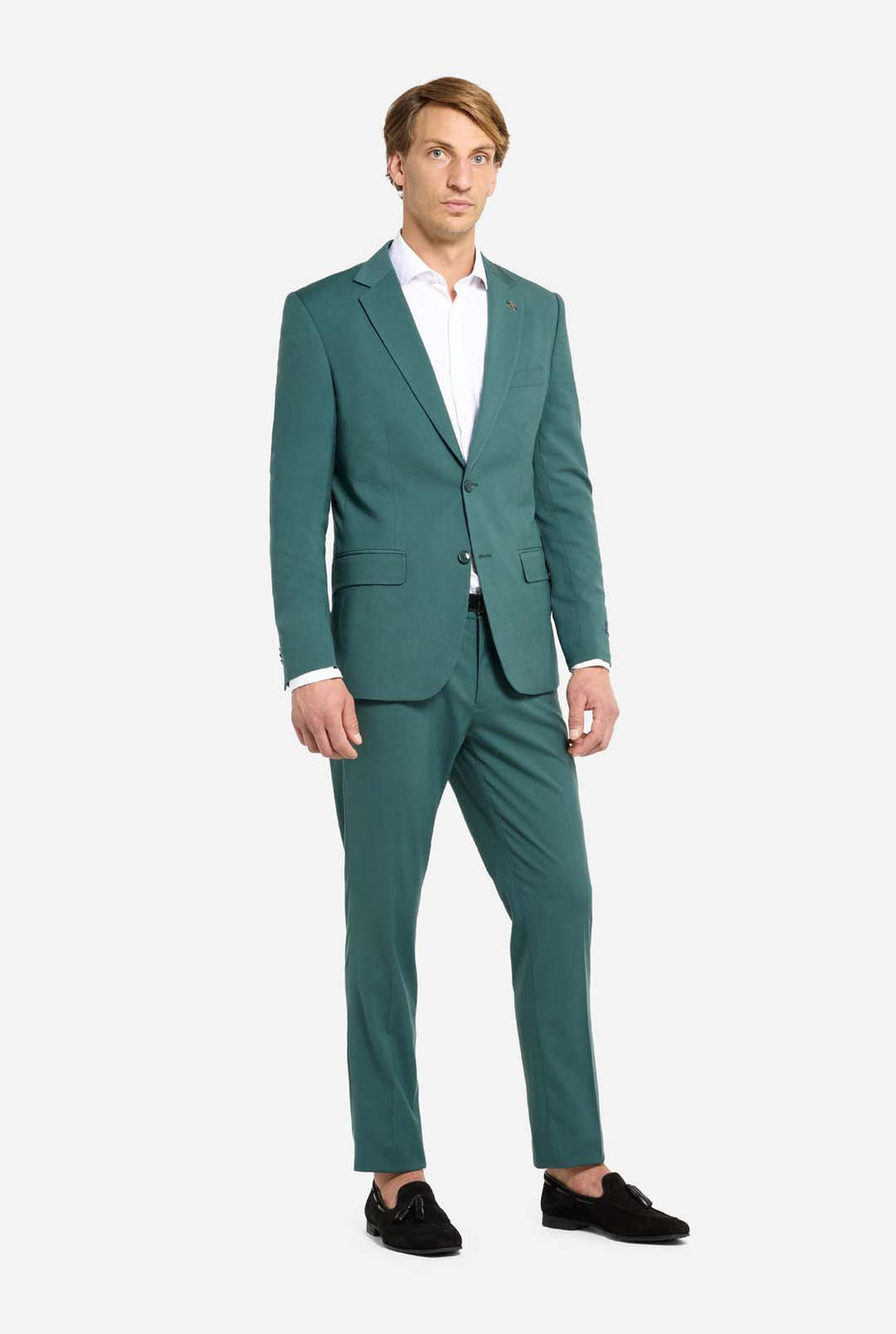 Afbeelding met lichtgrijze achtergrond en een man in een donkergroen herenpak en wit overhemd. Het pak bestaat uit een blazer en een pantalon. De man kijkt zijwaarts.