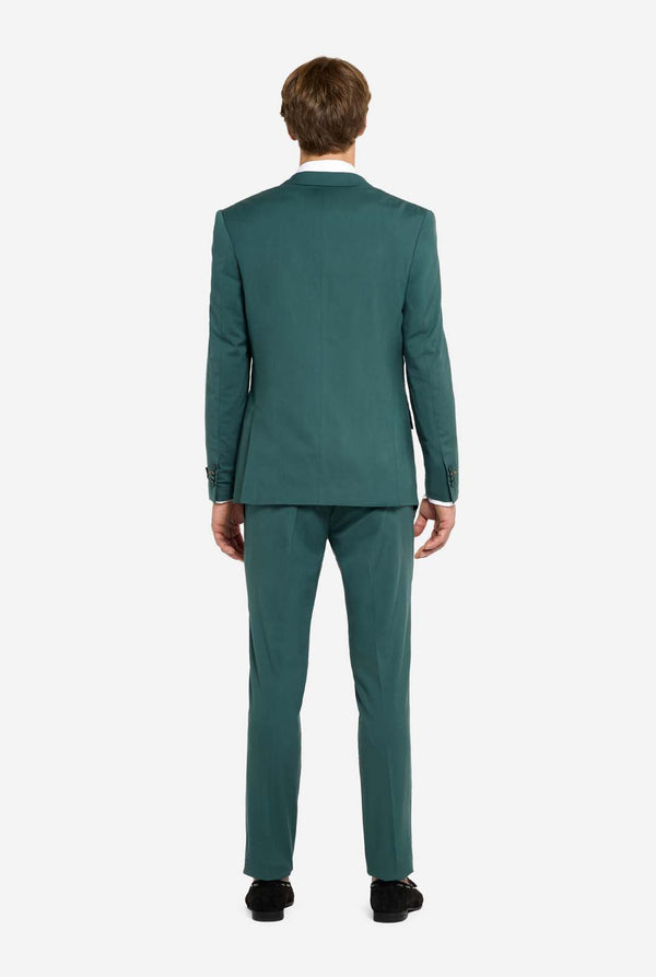 Afbeelding met lichtgrijze achtergrond en een man in een donkergroen herenpak en wit overhemd. Het pak bestaat uit een blazer en een pantalon. Zicht vanaf de achterkant