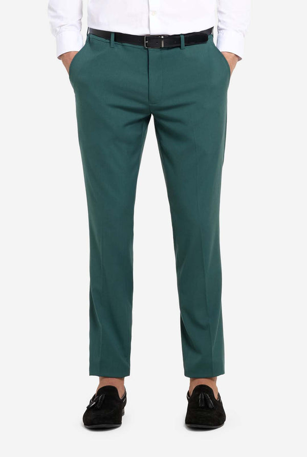 Afbeelding met lichtgrijze achtergrond en een man in een donkergroen herenpak en wit overhemd. Het pak bestaat uit een blazer en een pantalon. Close up van de broek