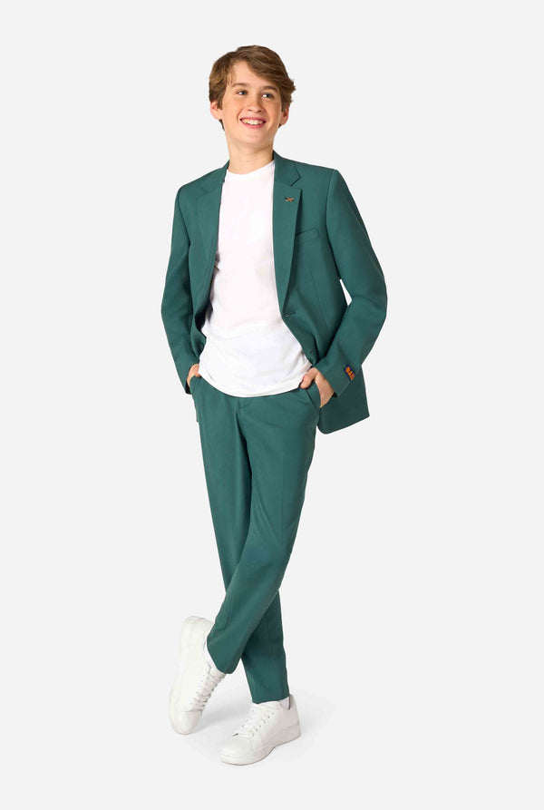 Tienerjongen draagt ​​een stijlvol donkergroen pak met een wit overhemd en glimlacht zelfverzekerd. Perfecte formele outfit voor speciale gelegenheden, bruiloften en feesten voor jongens. Volledig lichaamsbeeld.