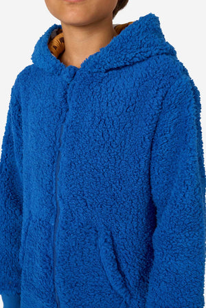 Jongen draagt blauwe Cookie Monster onesie, gefocust op de borst