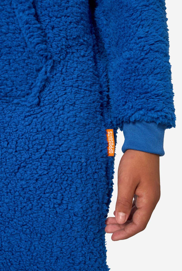 Jongen draagt blauwe Cookie Monster onesie, gefocust op de mouwen