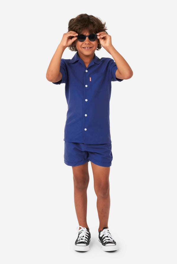 Jongen draagt ​​donkerblauwe zomerset, bestaande uit korte broek en shirt, volledig lichaamsbeeld