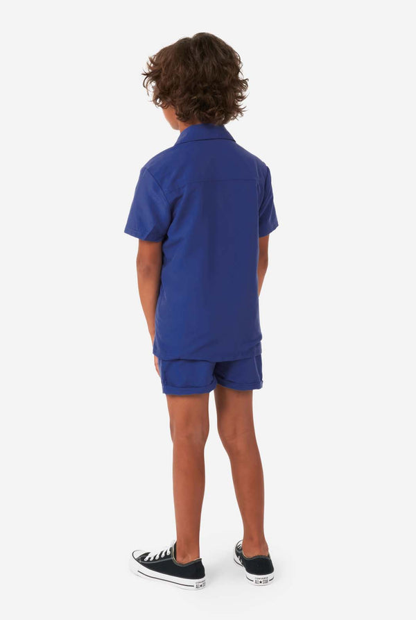Jongen draagt ​​donkerblauwe zomerset, bestaande uit korte broek en shirt, gezien vanaf de achterkant
