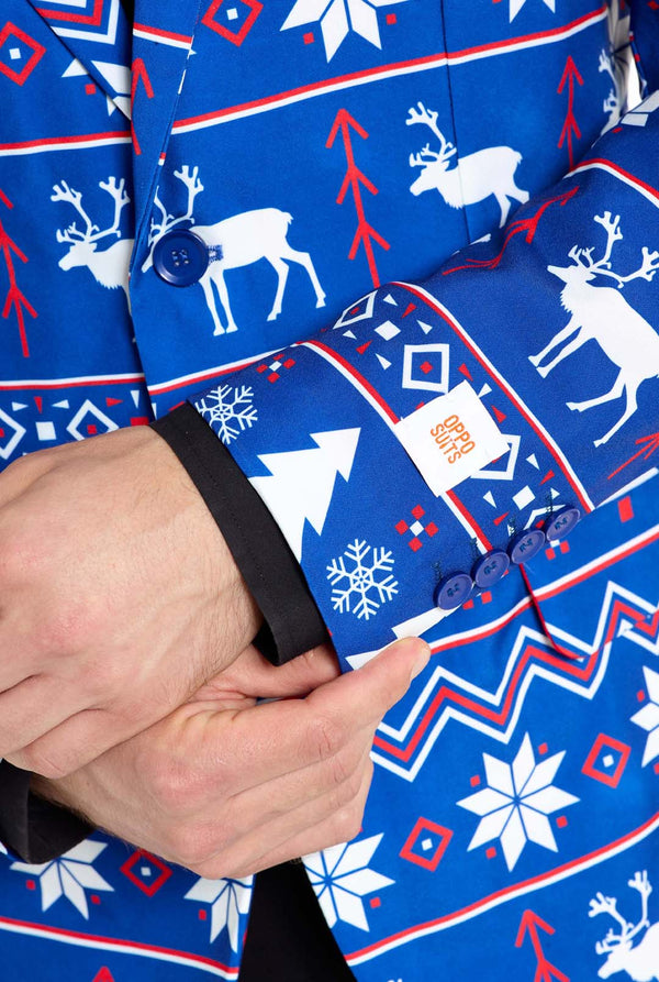 Man met blauwe kerstblazer voor mannen met Noordse kerstfiguren. Man draagt ​​ook een zwarte broek en een zwart herenoverhemd. Mouw close-up.
