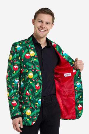 Man met groene kerstblazer voor heren met versierde kerstboomprint. Man draagt ​​ook een zwarte broek en een zwart herenoverhemd. Resultaat rode binnenkant van de jas.