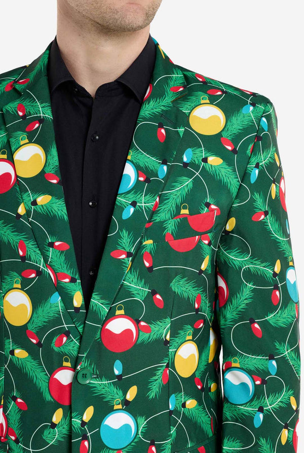 Man met groene kerstblazer voor heren met versierde kerstboomprint. Man draagt ​​ook een zwarte broek en een zwart herenoverhemd. Borst close-up.