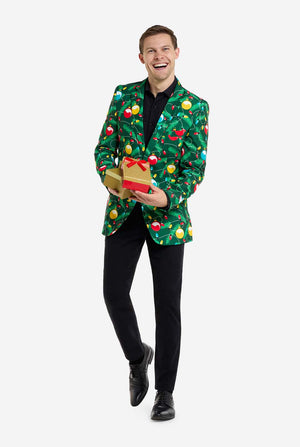 Man met groene kerstblazer voor heren met versierde kerstboomprint. Man draagt ​​ook een zwarte broek en een zwart herenoverhemd. Cadeautjes vasthouden.