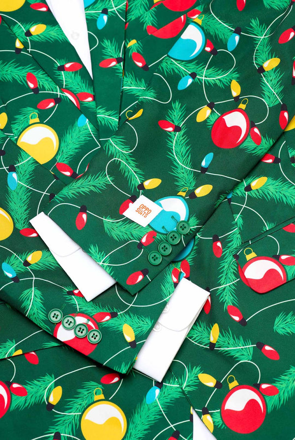 Man met groene kerstblazer voor heren met versierde kerstboomprint. Close-up met wit overhemd.