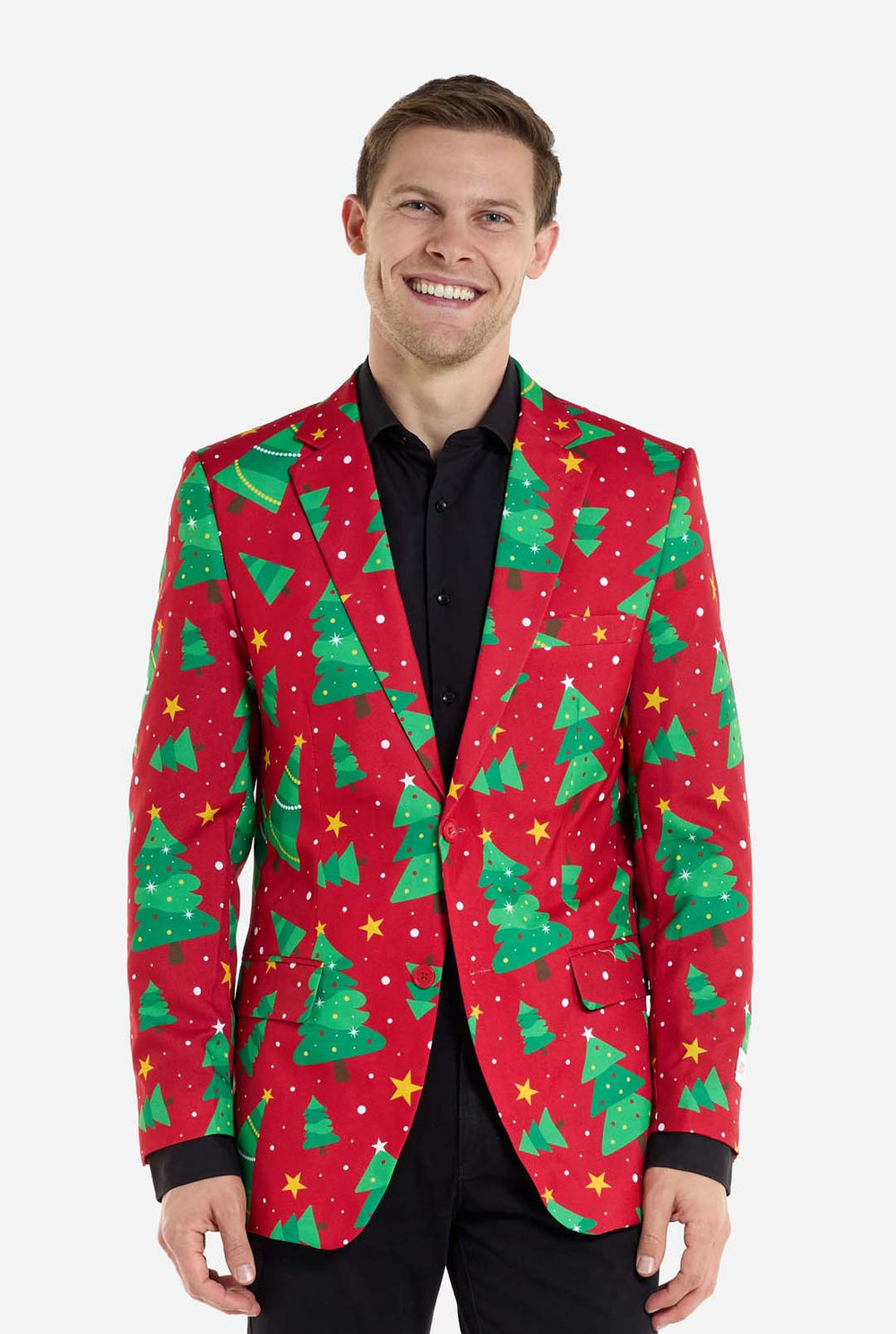 Man met rode kerstblazer voor heren met kerstbomen en sterrenprint. Man draagt ​​ook een zwarte broek en een zwart herenoverhemd.
