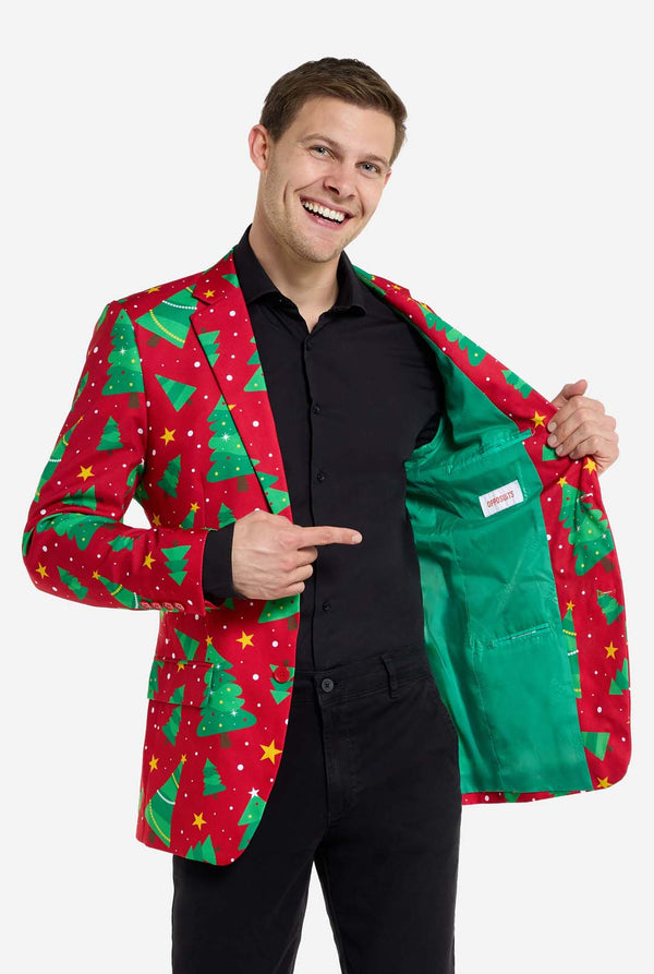 Man met rode kerstblazer voor heren met kerstbomen en sterrenprint. Man draagt ​​ook een zwarte broek en een zwart herenoverhemd. Resultaat groene binnenkant van de jas.