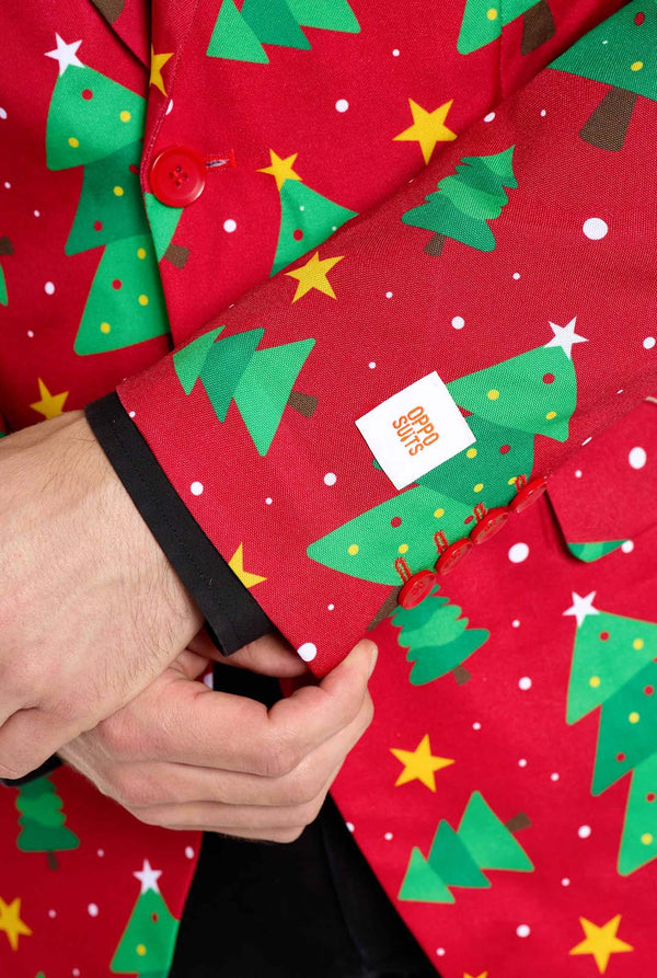 Man met rode kerstblazer voor heren met kerstbomen en sterrenprint. Man draagt ​​ook een zwarte broek en een zwart herenoverhemd. Mouw close-up.
