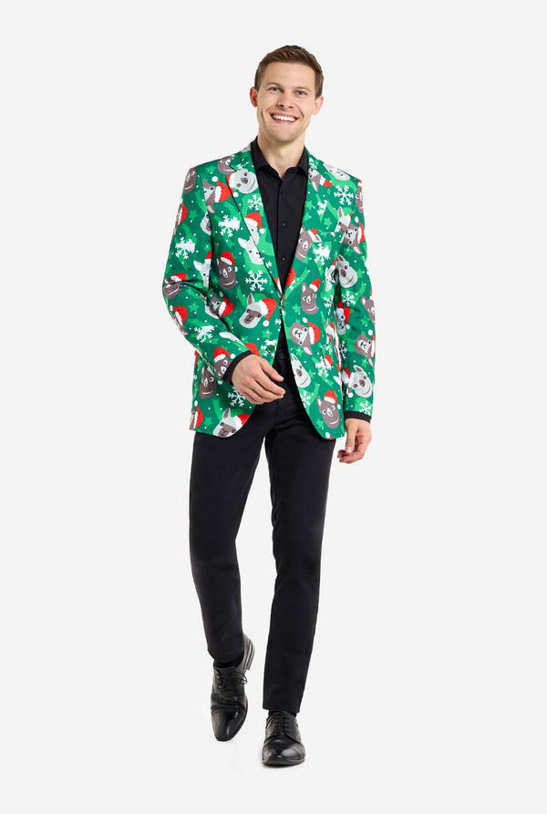 Man met groene kerstblazer voor mannen met kerstlama's. Man draagt ​​ook een zwarte broek en een zwart herenoverhemd. Volledig lichaamsbeeld.