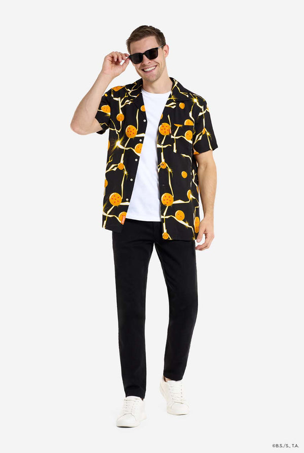 Man draagt zwart Hawaiiaans shirt met Dragon Ball Z-print, met Dragon Balls en bliksem. Volledig beeld met zonnebril.