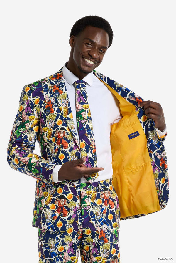 Man draagt ​​een herenpak met een all-over print van Dragon Ball Z, waarop de Dragon Ball-personages staan ​​afgebeeld. Het pak bestaat uit een blazer, een pantalon en een stropdas. Hij houdt een kant van de blazer open.