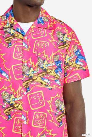 Man draagt ​​roze zomerset bestaande uit shirt en shorts. De zomerset heeft een Dragon Ball Z vechtende Goku en Vegeta print. Shirt close up.