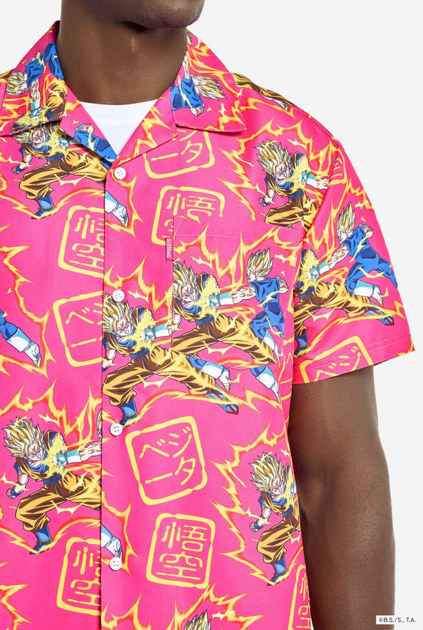 Man draagt ​​roze zomerset bestaande uit shirt en shorts. De zomerset heeft een Dragon Ball Z vechtende Goku en Vegeta print. Shirt close up.