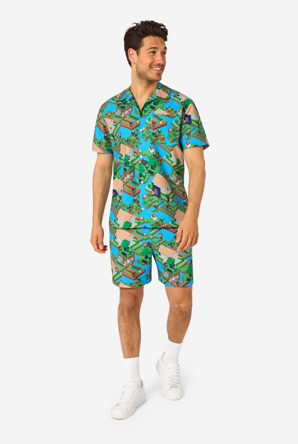 Een man draagt een kleurrijke zomeroutfit met een Minecraft Overworld print, met pixelachtige landschappen, personages en elementen uit het iconische spel. Het shirt met korte mouwen en de bijpassende shorts benadrukken een levendig ontwerp geïnspireerd door het Minecraft-universum.