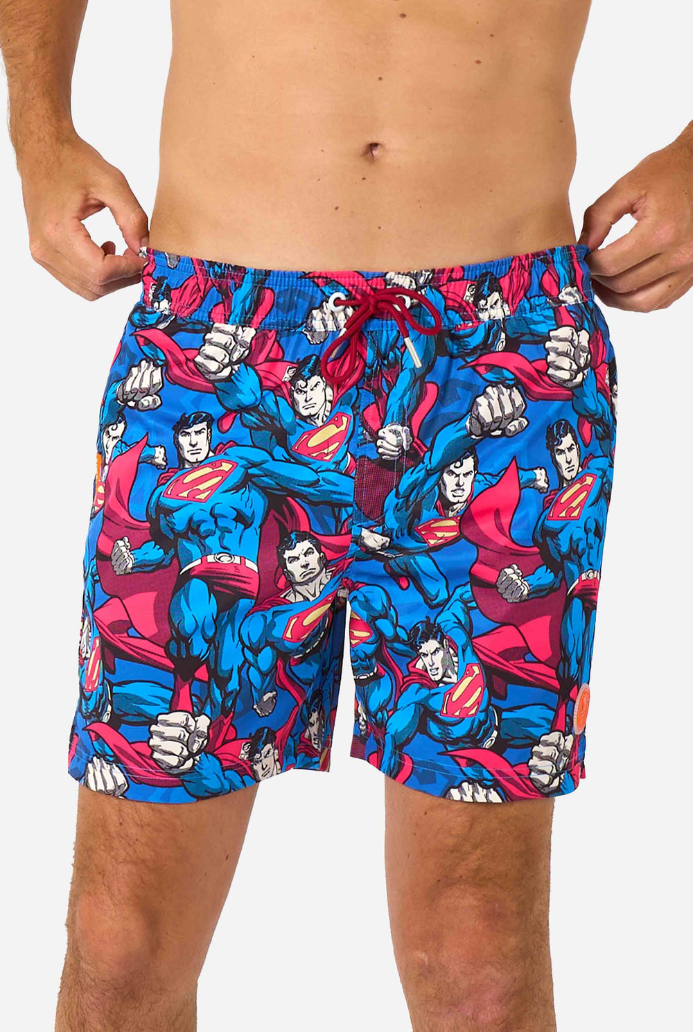 Man draagt ​​een zwembroek met Superman-thema voor heren met een opvallend stripboekontwerp met meerdere actieposes van de Man of Steel. Perfect voor superheldenfans die een spetter willen maken. Close-up van het middel.