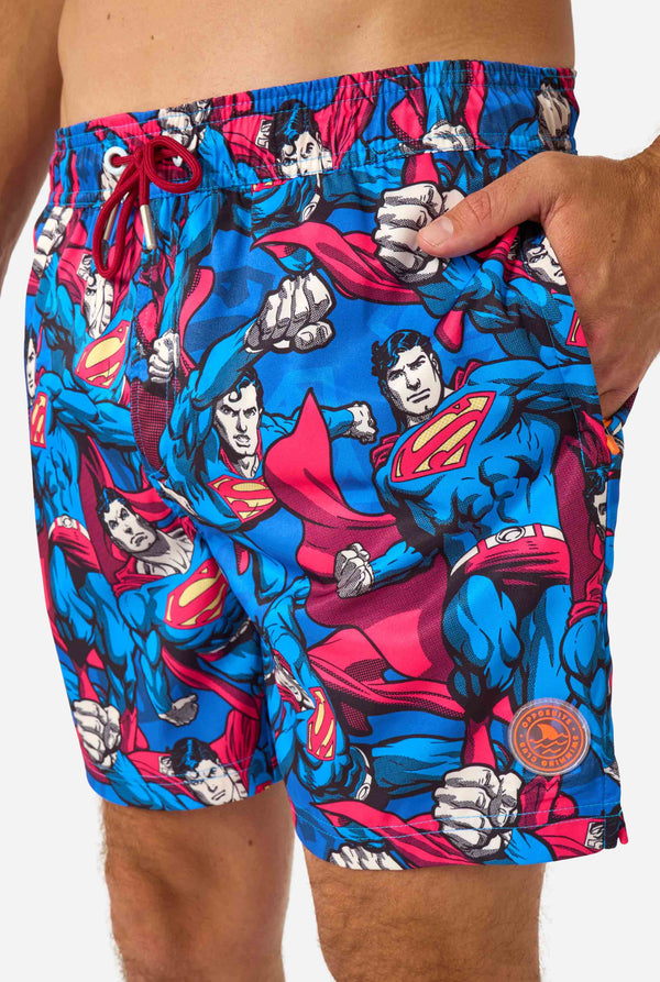 Man draagt ​​een zwembroek met Superman-thema voor heren met een opvallend stripboekontwerp met meerdere actieposes van de Man of Steel. Perfect voor superheldenfans die een spetter willen maken. Close-up voorkant.