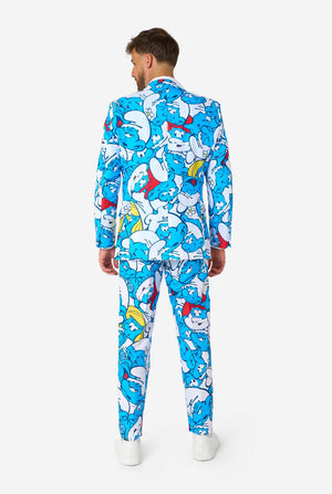 Man gekleed in een kleurrijk herenpak van de Smurfen met een all-over cartoonprint in de kleuren blauw, wit, rood en geel, inclusief bijpassende stropdas en wit overhemd, staande tegen een effen achtergrond. Gezien vanaf de achterkant.
