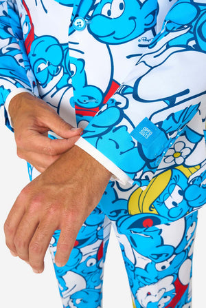 Man gekleed in een kleurrijk herenpak van de Smurfen met een all-over cartoonprint in de kleuren blauw, wit, rood en geel, inclusief bijpassende stropdas en wit overhemd, staande tegen een effen achtergrond. Close up van de mouwen