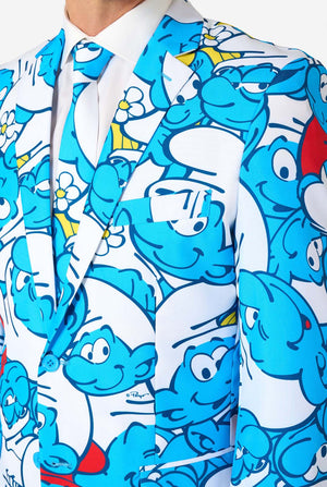 Man gekleed in een kleurrijk herenpak van de Smurfen met een all-over cartoonprint in de kleuren blauw, wit, rood en geel, inclusief bijpassende stropdas en wit overhemd, staande tegen een effen achtergrond. Close up van de borst.