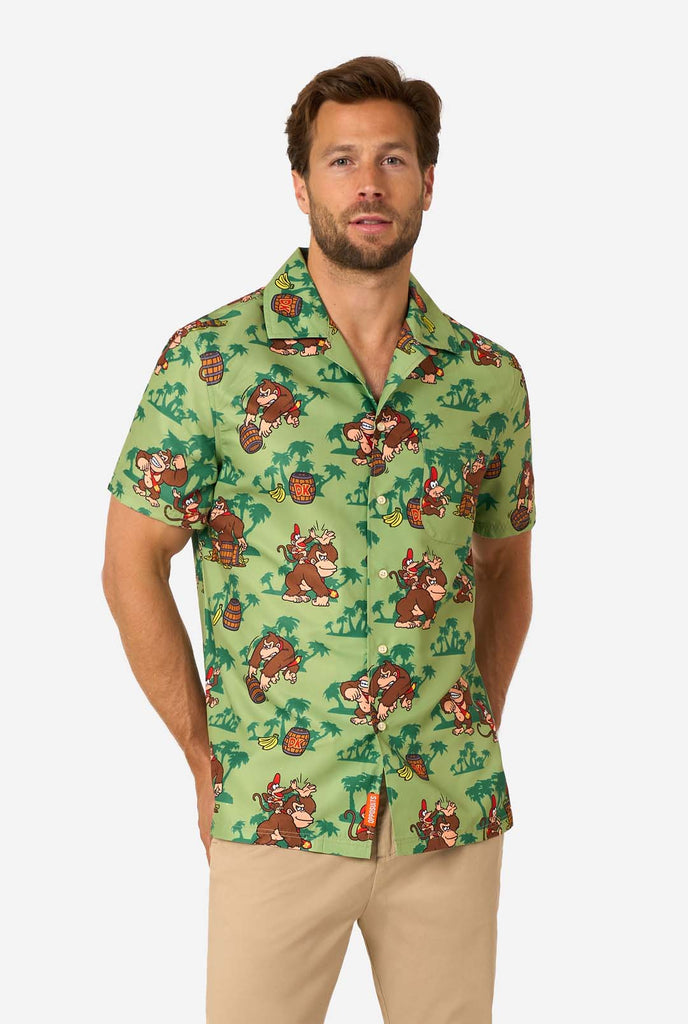 Afbeelding van een man die een Hawaiiaans shirt met Donkey Kong-thema draagt. Het shirt heeft een lichtgroene achtergrond en bevat donkergroene palmbomen, en meerdere afbeeldingen van het personage Donkey Kong, uit Super Mario. De man kijkt in de camera.