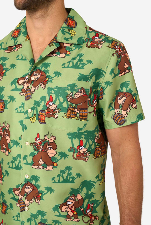 Afbeelding van een man die een Hawaiiaans shirt met Donkey Kong-thema draagt. Het shirt heeft een lichtgroene achtergrond en bevat donkergroene palmbomen, en meerdere afbeeldingen van het personage Donkey Kong, uit Super Mario. Close-up van de borst.