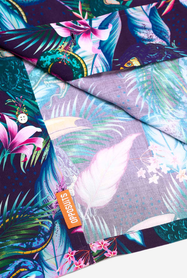 Een afbeelding van een paars Hawaï-shirt met een tropische print, die lijkt op het jungle-nachtleven. De print bestaat uit papegaaien, slangen, bladeren en bloemen. Close-up.