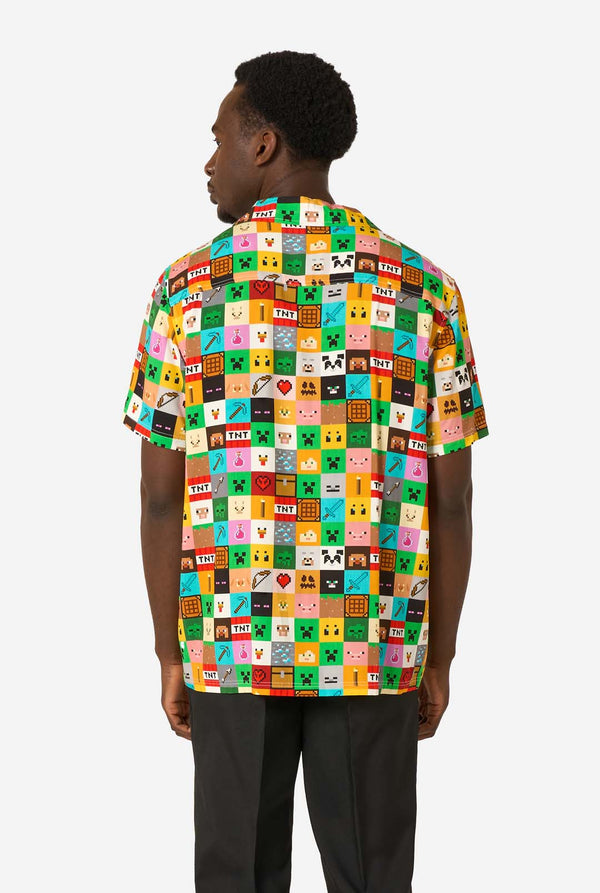Man met een kleurrijk Minecraft Hawaiiaans shirt met gepixelde blokken, personages en items uit de game, gecombineerd met een zwarte broek, staande tegen een effen witte achtergrond. Zicht vanaf de achterkant