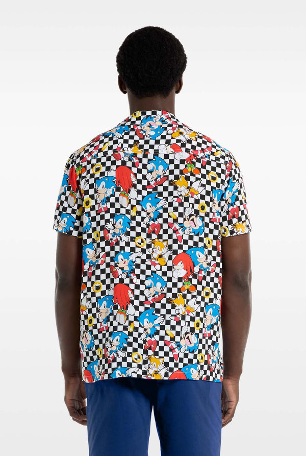 Een man draagt een zwart-wit geruit Hawaï-shirt met personages uit de Sonic the Hedgehog-franchise en gouden ringen erop. Foto van de achterkant