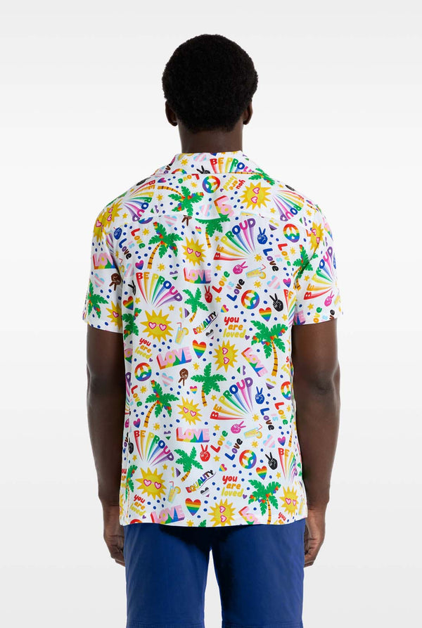 Een man draagt ​​een wit Hawaiiaans shirt met een regenboogprint. De print bestaat uit vredessymbolen, hartjes en andere iconen. Hij draagt ​​ook een blauwe broek. Beeld van de achterkant.