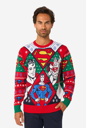 Man in een kleurrijke gebreide kersttrui met verschillende Superman-prints en het iconische “S”-logo.