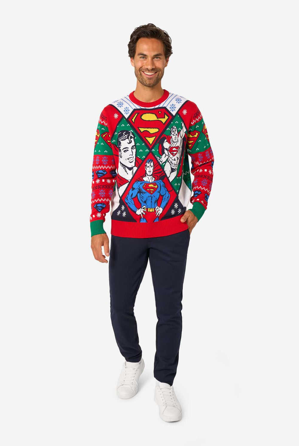 Man in een kleurrijke gebreide kersttrui met verschillende Superman-prints en het iconische “S”-logo.