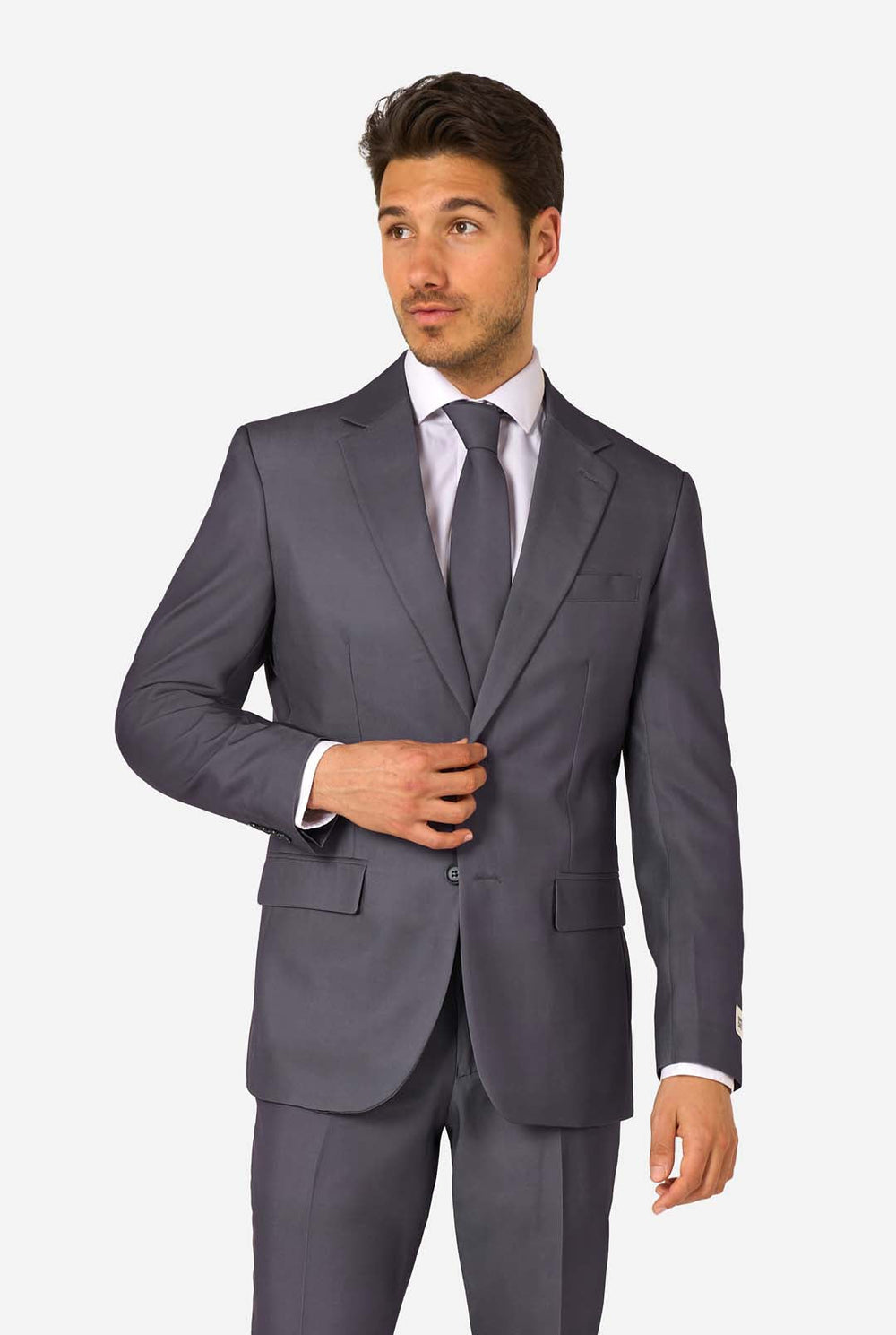 Een man draagt ​​een stijlvol antracietgrijs pak met een wit overhemd en ziet er zelfverzekerd uit. Perfecte formele outfit voor speciale gelegenheden, bruiloften en feesten. Hij kijkt zijwaarts.