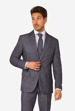 Een man draagt ​​een stijlvol antracietgrijs pak met een wit overhemd en ziet er zelfverzekerd uit. Perfecte formele outfit voor speciale gelegenheden, bruiloften en feesten. Hij kijkt zijwaarts.