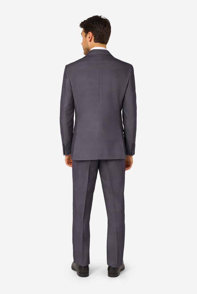 Een man draagt ​​een stijlvol antracietgrijs pak met een wit overhemd en ziet er zelfverzekerd uit. Perfecte formele outfit voor speciale gelegenheden, bruiloften en feesten. Beeld van de achterkant.