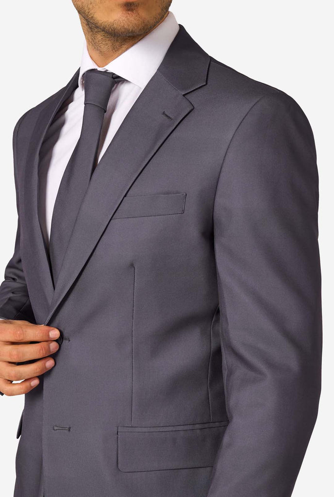 Een man draagt ​​een stijlvol antracietgrijs pak met een wit overhemd en ziet er zelfverzekerd uit. Perfecte formele outfit voor speciale gelegenheden, bruiloften en feesten. Close-up.
