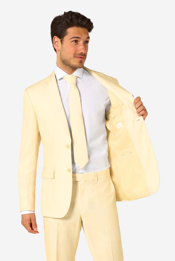 Elegant herenpak in een zachte pastelgele tint, perfect voor bruiloften, zomerse evenementen en formele gelegenheden. Dit stijlvolle maatpak heeft een slim fit, inkepingen in de revers en een bijpassende stropdas voor een verfijnde look. Ideaal voor moderne heren die een statement willen maken met een licht pastelkleurig pak. Man houdt 1 kant van jasje open.