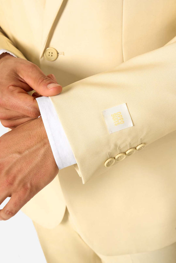 Elegant herenpak in een zachte pastelgele tint, perfect voor bruiloften, zomerse evenementen en formele gelegenheden. Dit stijlvolle maatpak heeft een slim fit, inkepingen in de revers en een bijpassende stropdas voor een verfijnde look. Ideaal voor moderne heren die een statement willen maken met een licht pastelkleurig pak. Close up mouw.