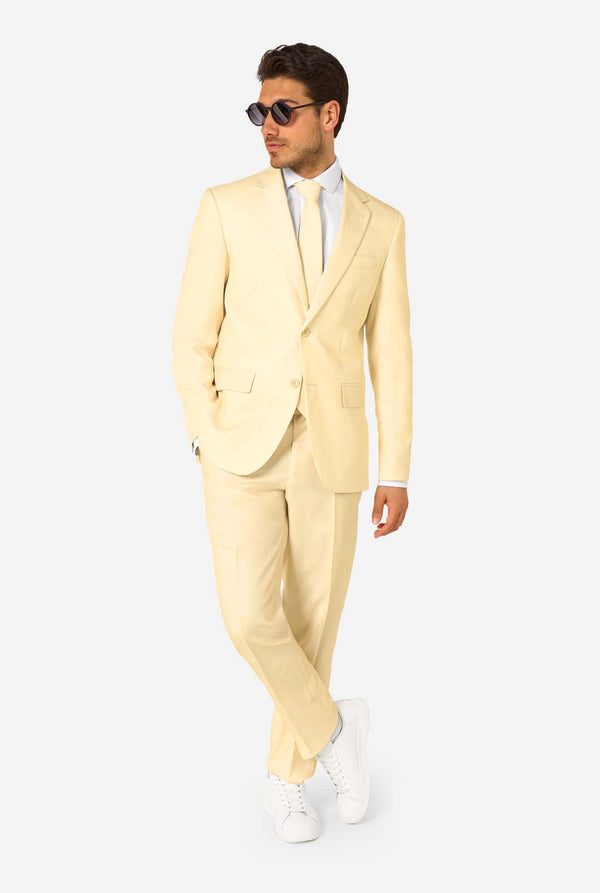 Elegant herenpak in een zachte pastelgele tint, perfect voor bruiloften, zomerse evenementen en formele gelegenheden. Dit stijlvolle maatpak heeft een slim fit, inkepingen in de revers en een bijpassende stropdas voor een verfijnde look. Ideaal voor moderne heren die een statement willen maken met een licht pastelkleurig pak. Volledig beeld en draagt zonnebril.