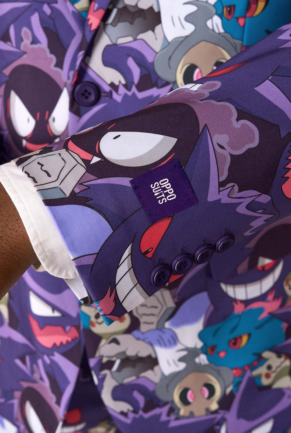 Een man draagt een pak met Ghost Pokemon-thema, een stropdas met Ghost Pokemon-thema en een wit overhemd op een witte achtergrond. Close up van de mouwen