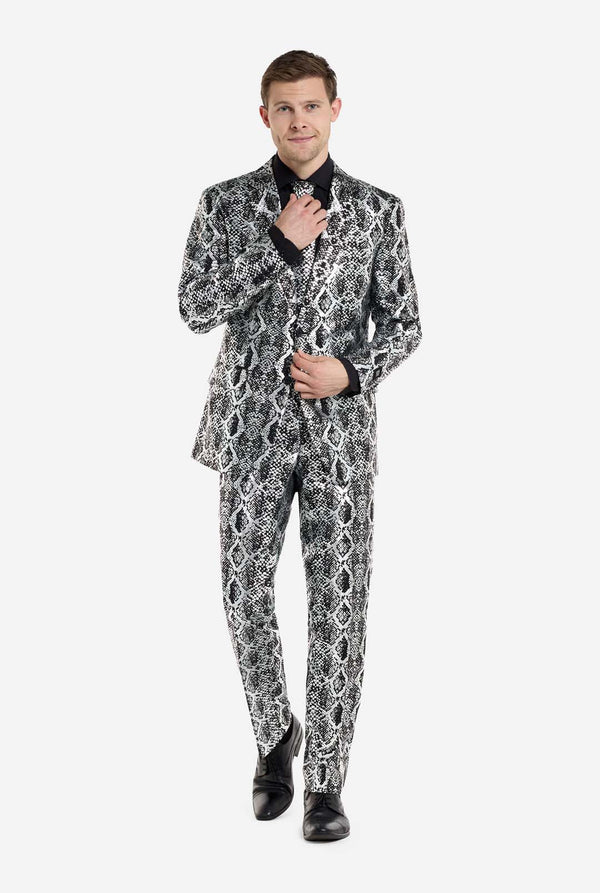 Een man draagt ​​een opvallend zilver-zwart pak met slangenprint van OppoSuits en zwarte schoenen. Het opvallende pak heeft een opvallend slangenpatroon en biedt een strakke, modieuze look, perfect voor feestjes, evenementen of voor het maken van een gedurfd modestatement. Het herenpak wordt gecombineerd met een zwart overhemd en een bijpassende stropdas met slangenprint, wat een verfijnd tintje toevoegt aan het geheel.