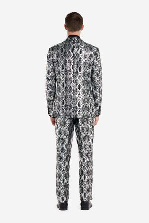 Een man draagt ​​een opvallend zilver-zwart pak met slangenprint van OppoSuits. Het opvallende pak heeft een opvallend slangenpatroon en biedt een strakke, modieuze look, perfect voor feestjes, evenementen of voor het maken van een gedurfd modestatement. Het herenpak wordt gecombineerd met een zwart overhemd en een bijpassende stropdas met slangenprint, wat een verfijnd tintje toevoegt aan het geheel. Uitzicht vanaf de achterkant.
