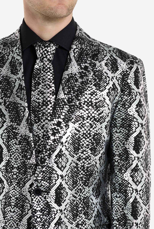 Een man draagt ​​een opvallend zilver-zwart pak met slangenprint van OppoSuits. Het opvallende pak heeft een opvallend slangenpatroon en biedt een strakke, modieuze look, perfect voor feestjes, evenementen of voor het maken van een gedurfd modestatement. Het herenpak wordt gecombineerd met een zwart overhemd en een bijpassende stropdas met slangenprint, wat een verfijnd tintje toevoegt aan het geheel. Borst close-up.